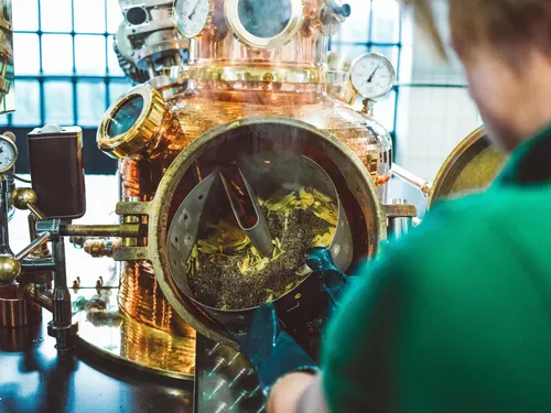 Distiller looking into the copper still through its porthole