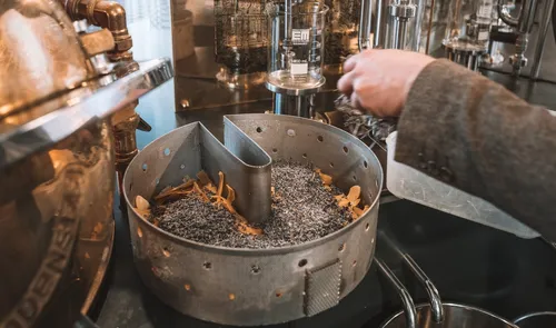 Distiller filling the percolation basket with botanicals