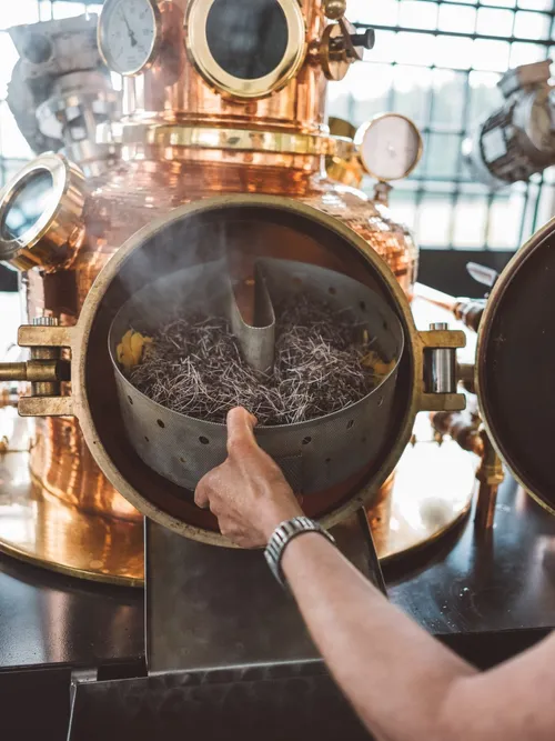 Distiller opening the copper still full of botanicals