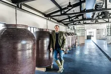 Monkey 47 founder standing beside earthenware vessels in the distillery