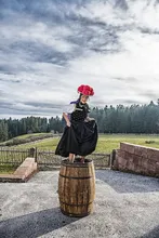 Woman in traditional Black Forest costume standing on a barrel