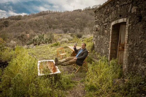 Man resting by a stone hut with a crate of lemons