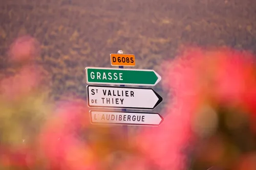 Road sign to Grasse behind blooming flowers in Provence