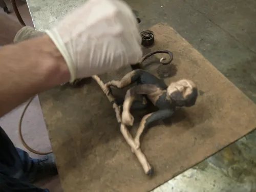 Craftsman with gloves working on the cast monkey figure of the Species Rara Award