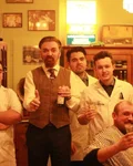 Barbers in white coats posing in a traditional barbershop