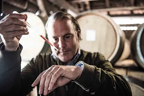 Man tasting a sample among barrels