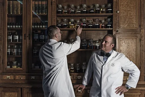 Two men in lab coats at an apothecary cabinet