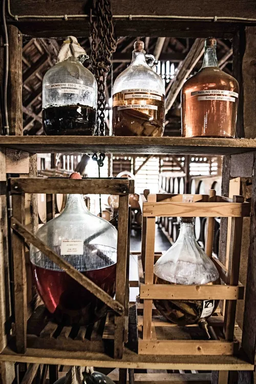 Glass carboys and distilling equipment on wooden shelves