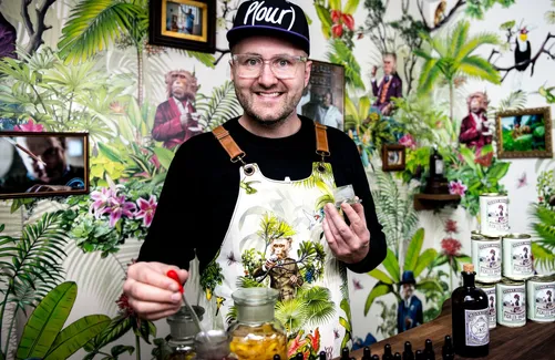 Bartender in cap and apron holding a pearl onion at the bar