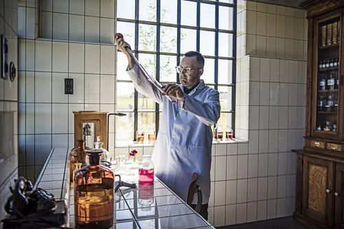 Man in lab coat holding up a test tube in the laboratory