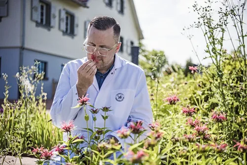Man in lab coat smelling a flower in the garden