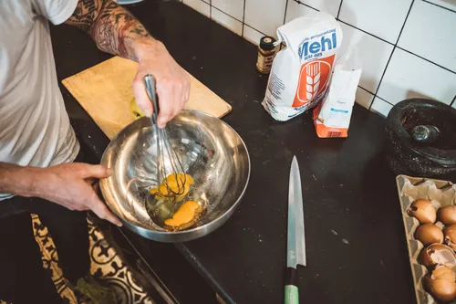 Chef whisking batter in a steel bowl