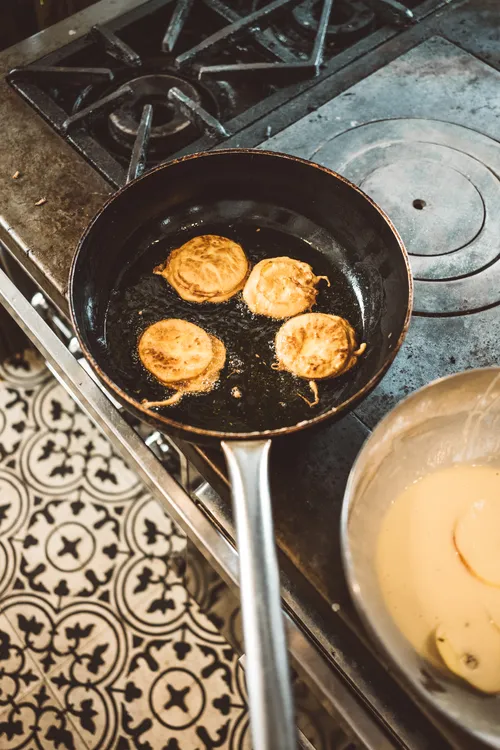 Apple fritters frying in a pan