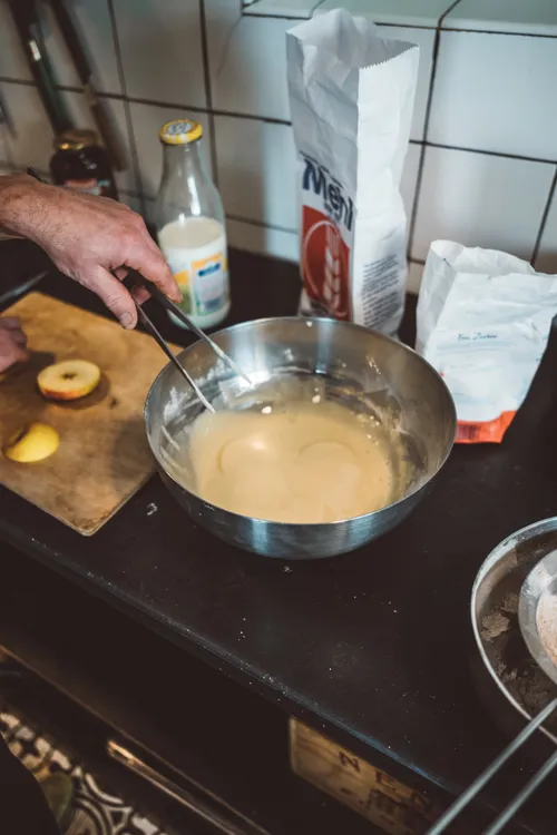 Bowl of batter next to sliced apples and ingredients
