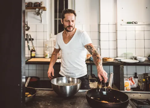 Tattooed chef cooking at the stove