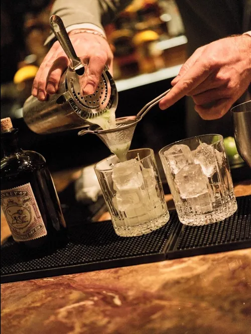 Bartender pouring cocktails into rocks glasses
