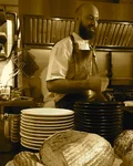 Chef at Burnt Ends in Singapore behind stacks of plates and bread