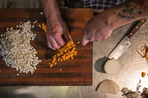 Hands dicing carrots and onions