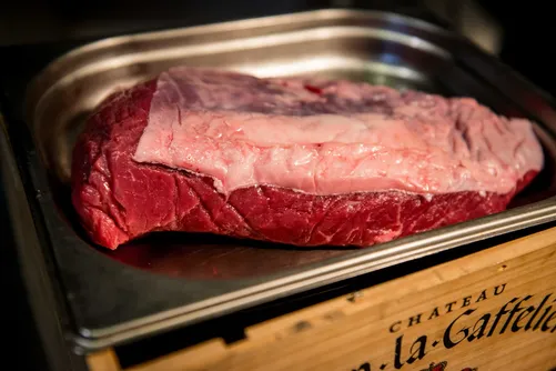 Raw beef joint in a steel tray on a wine crate