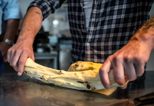 Hands stretching raisin dough into a strand