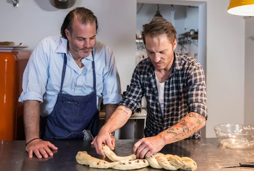 Two chefs braiding a Swabian yeast plait at a kitchen counter