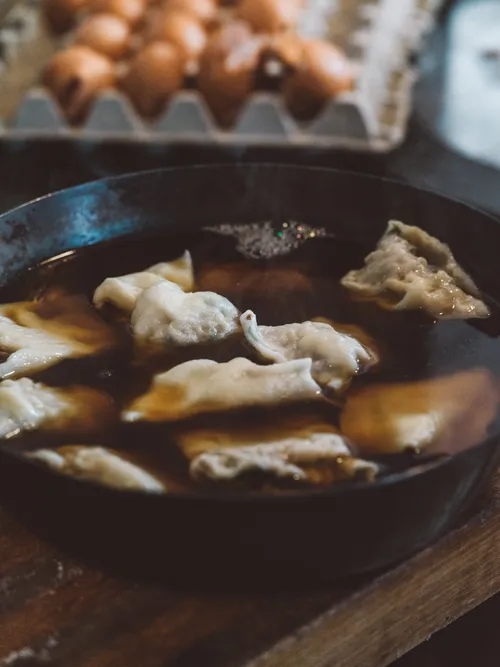 Maultaschen simmering in broth in a cast-iron pan