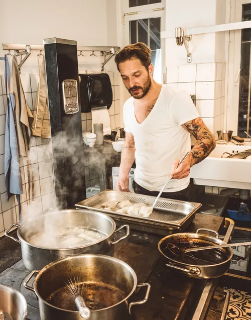 Chef cooking at the stove in a tiled kitchen