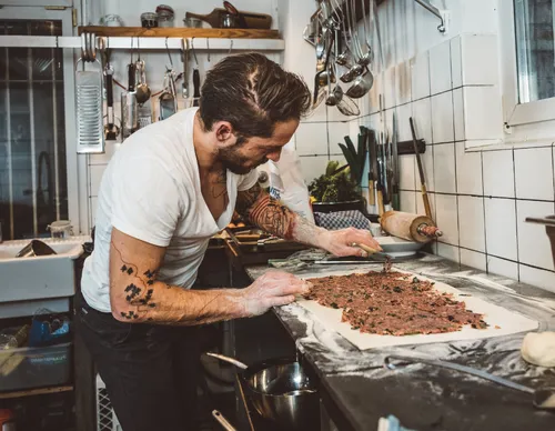 Chef spreading filling onto pasta dough in a restaurant kitchen