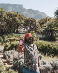 Man holding a Monkey 47 bottle in a garden with Table Mountain behind