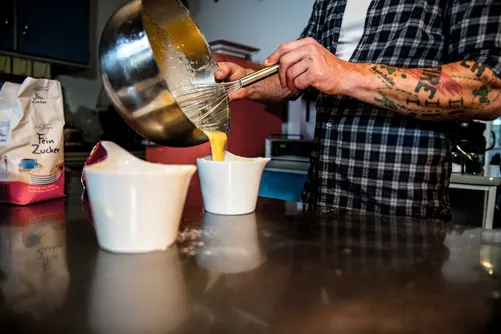 Chef pouring batter into white ceramic spoons
