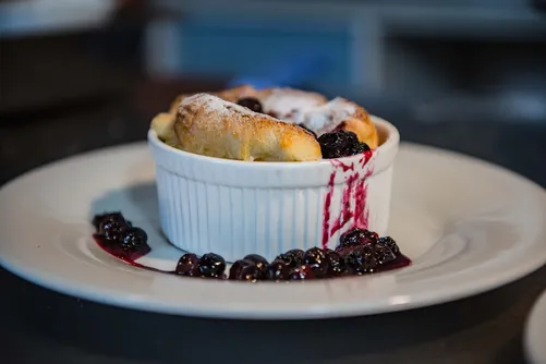 Ramekin dessert with dusted sugar and berry sauce