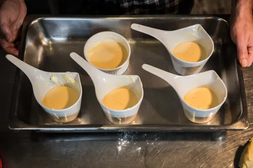 Ceramic dessert spoons filled with custard on a steel tray