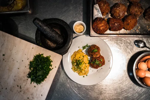 Plated meat patties with potato salad, herbs and eggs on the counter