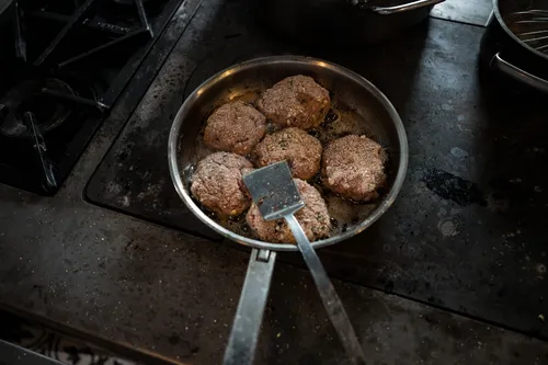 Meat patties frying in a cast-iron pan