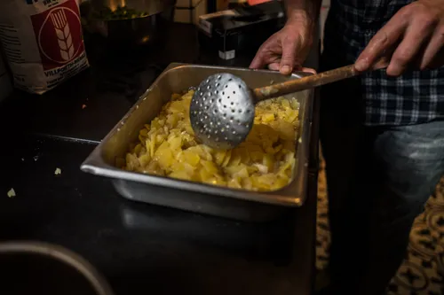 Stirring potato salad with a slotted spoon