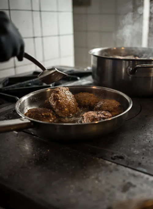 Meat patties frying in a pan on the stove