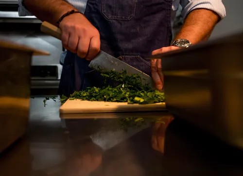 Chef chopping parsley on a wooden board