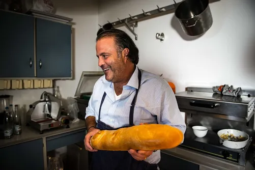 Chef smiling and holding a loaf of bread in the kitchen