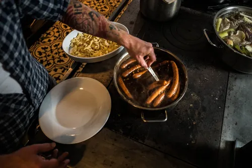 Chef plating sausages in a busy kitchen