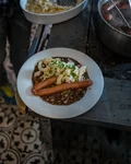 Plate of sausages with lentils and Spätzle on a tiled kitchen floor
