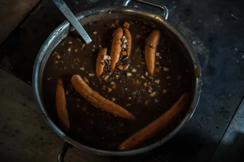 Sausages simmering in a dark sauce