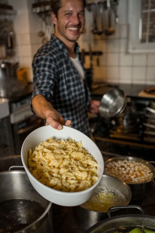 Smiling chef holding a bowl of Spätzle
