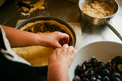 Placing plums on the dough in a cake tin
