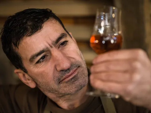 Distiller examining Barrel Cut in a tasting glass