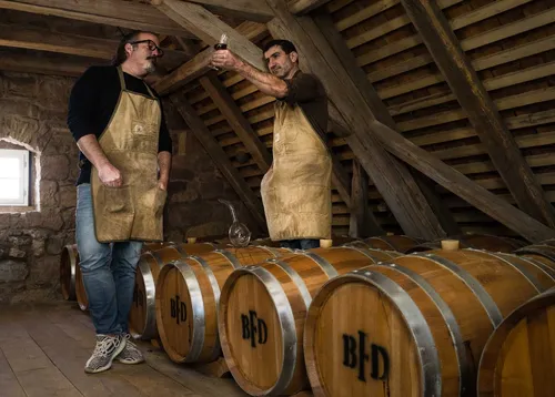 Distillers in aprons tasting from oak barrels