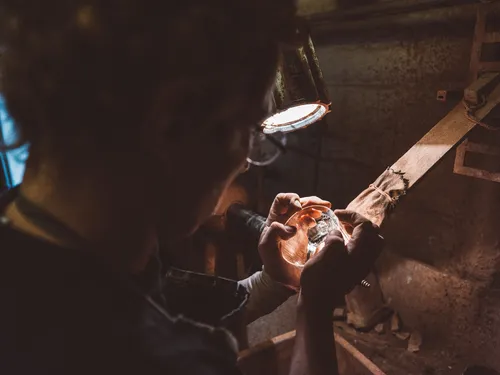 Craftsman examining a crystal piece under a lamp