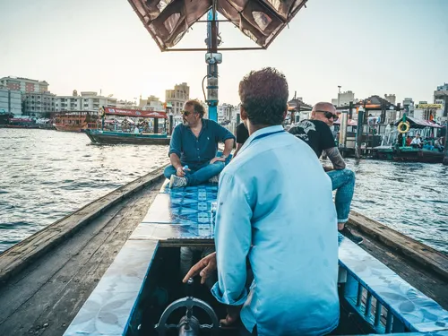 Two men riding an abra boat across Dubai Creek