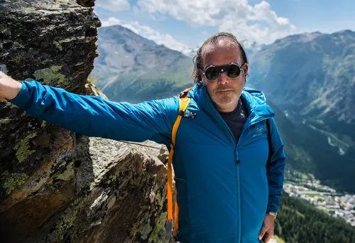 Man in sunglasses leaning on a rock in the mountains