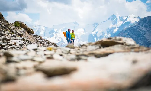 Two climbers on a rocky ridge with snowy peaks