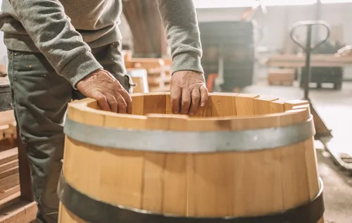Hands fitting staves of a new oak barrel